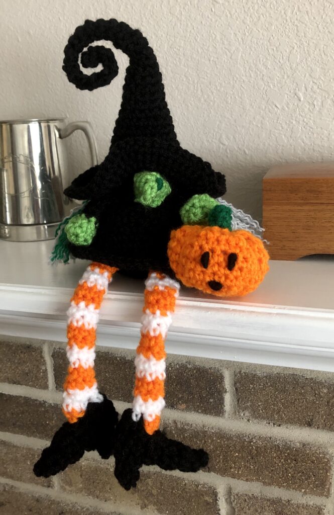 crocheted witch with baby jack-o-lantern sitting on mantle