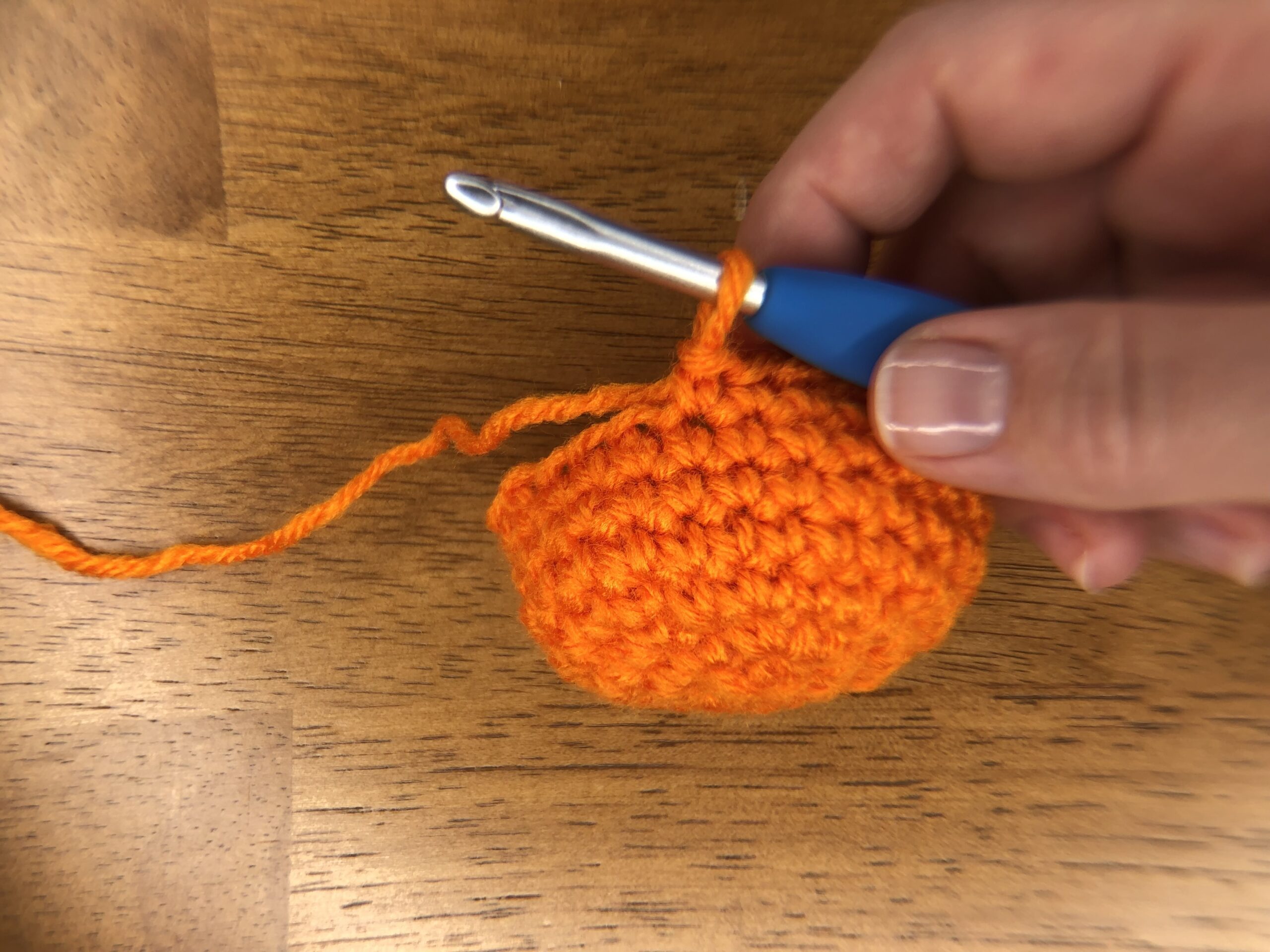 small orange crocheted half circle starting a baby jack-o-lantern pumpkin