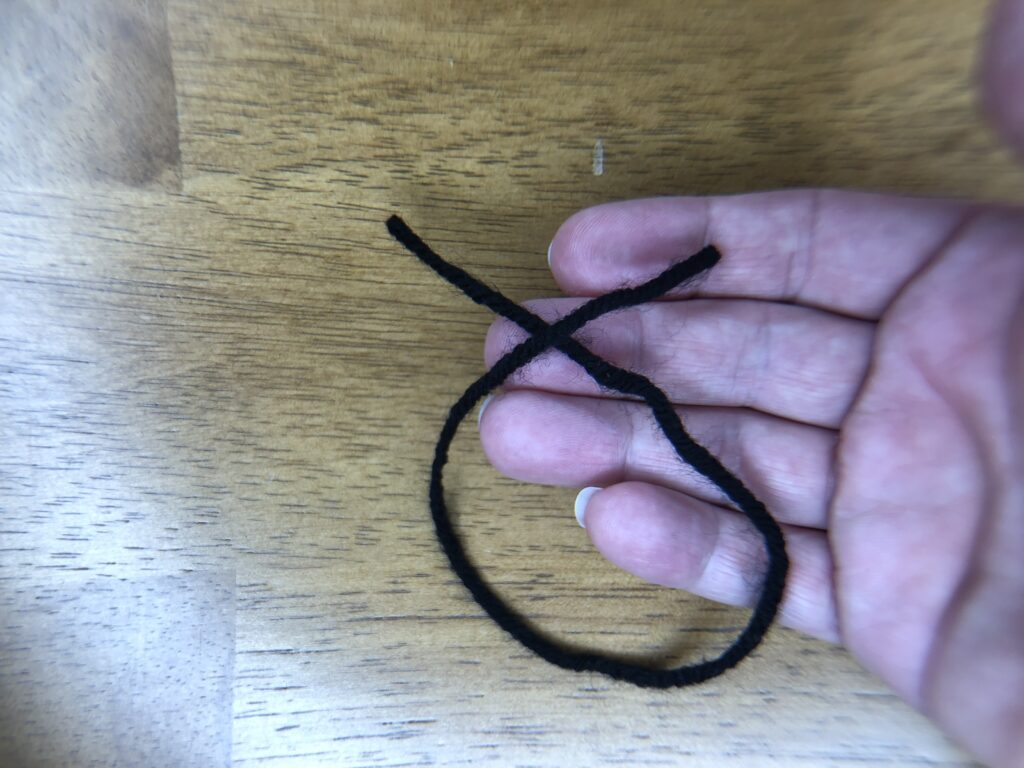 loop and cross of black yarn as first step for making knot eyes