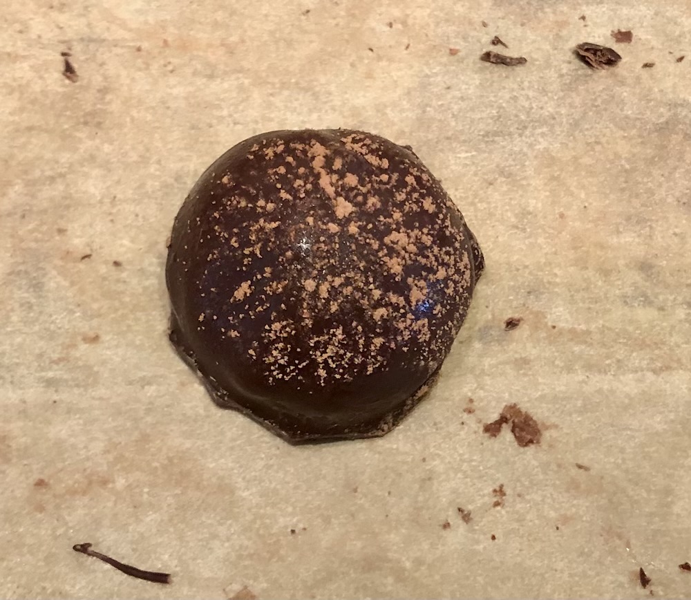 Single tiramisu chocolate covered cake ball dusted with cocoa powder
