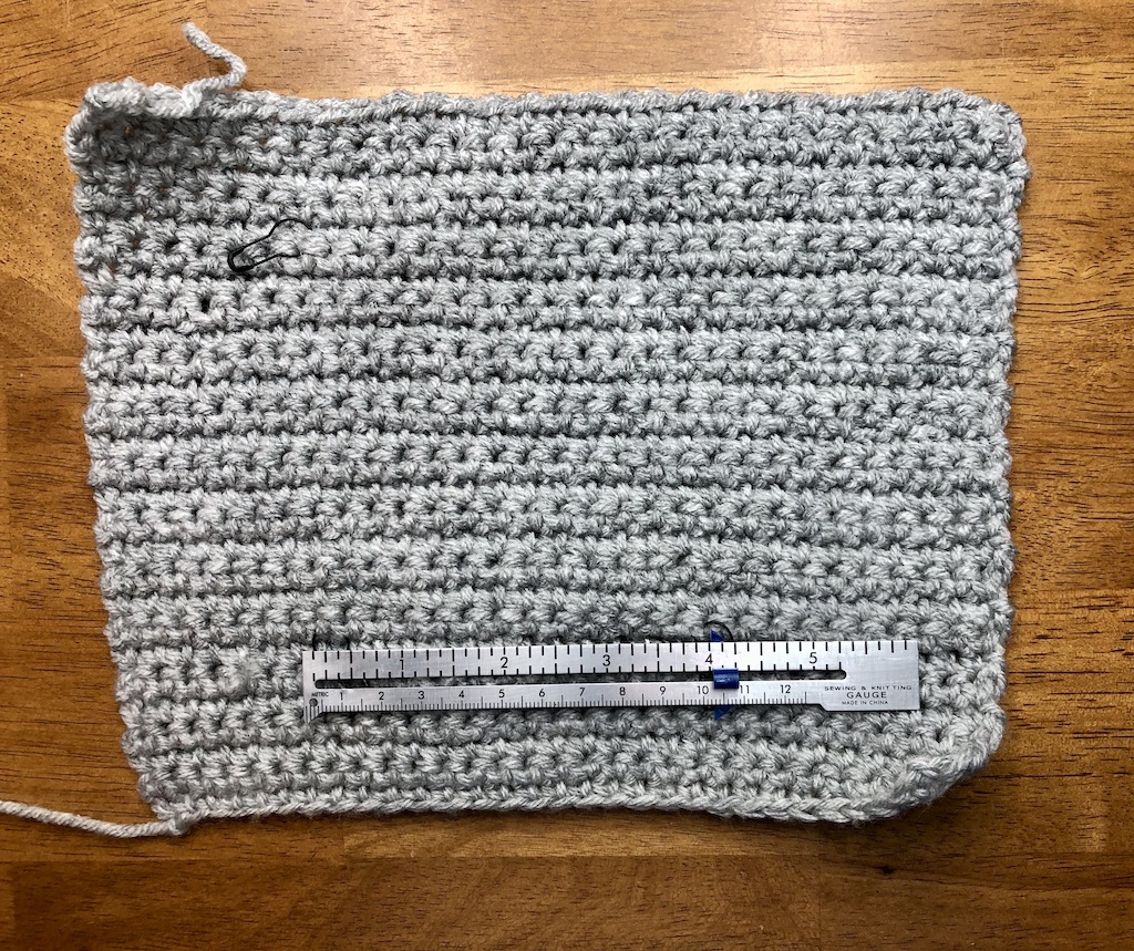 How to make a crochet swatch using light gray yarn and the single crochet stitch, with a measuring ruler to check the gauge.