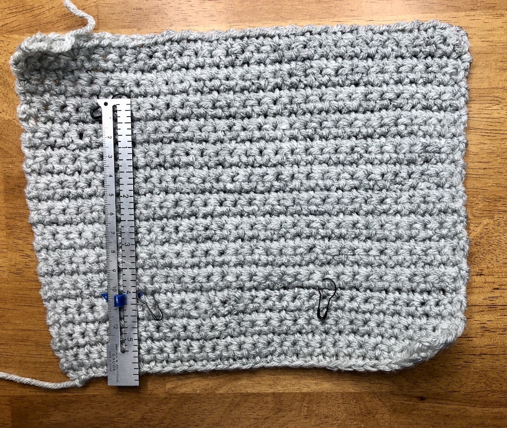 How to make a crochet swatch using light gray yarn and the single crochet stitch, with a measuring ruler to check the gauge.