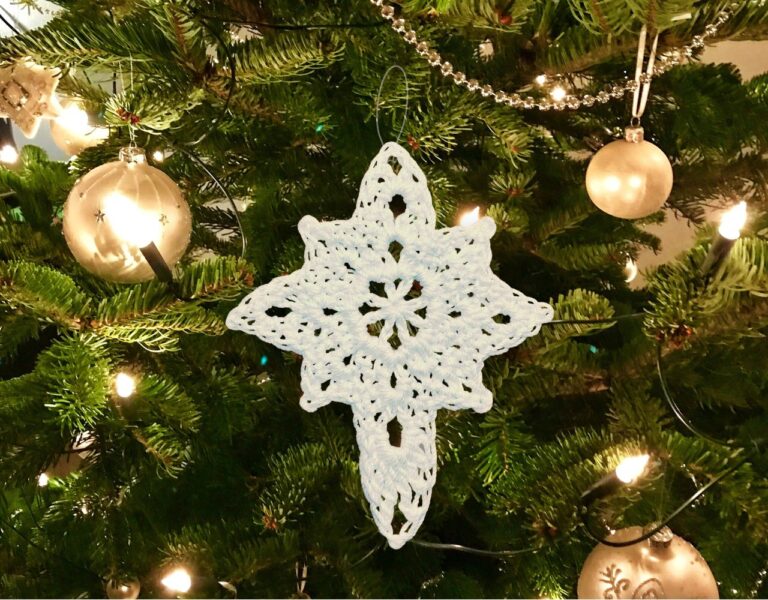 White Crocheted Christmas Star ornament hanging in a tree.