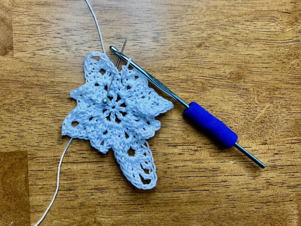 christmas star ornament with pin showing location for final slip stitch