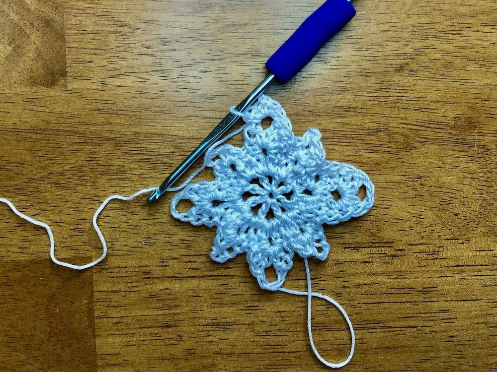 white christmas star ornament showing completed stitch grouping in the 3rd chain 3 loop in the 4th round