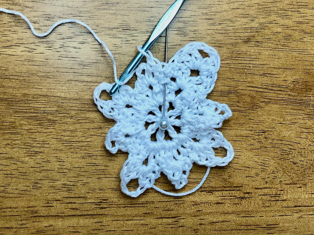 white christmas star ornament with pin showing skipped stitch location in 4th round