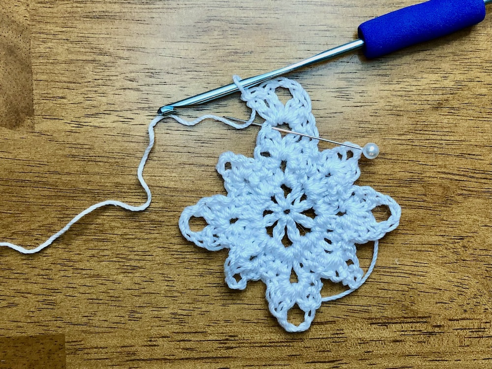 white christmas star ornament with pin showing skipped stitch location in 4th round