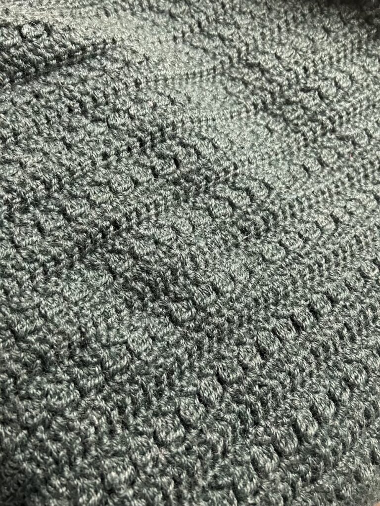 close up of green gray crocheted blanket.