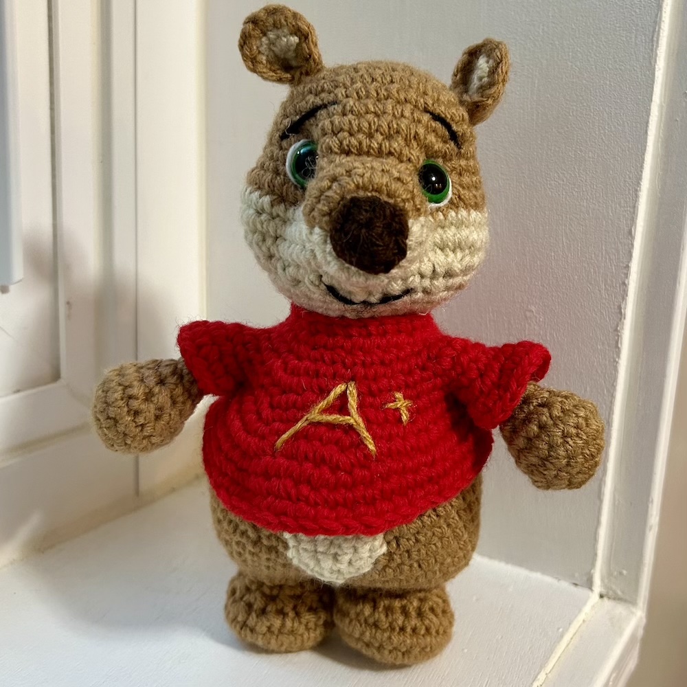 crocheted chipmunk doll wearing a red shirt with "A+" embroidered in gold thread.