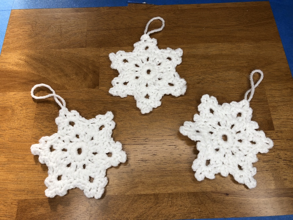 three snowflake ornaments on a wooden table