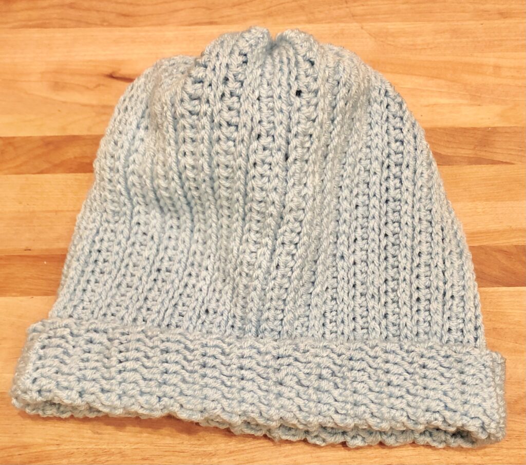 light blue crocheted beanie on a wood background.