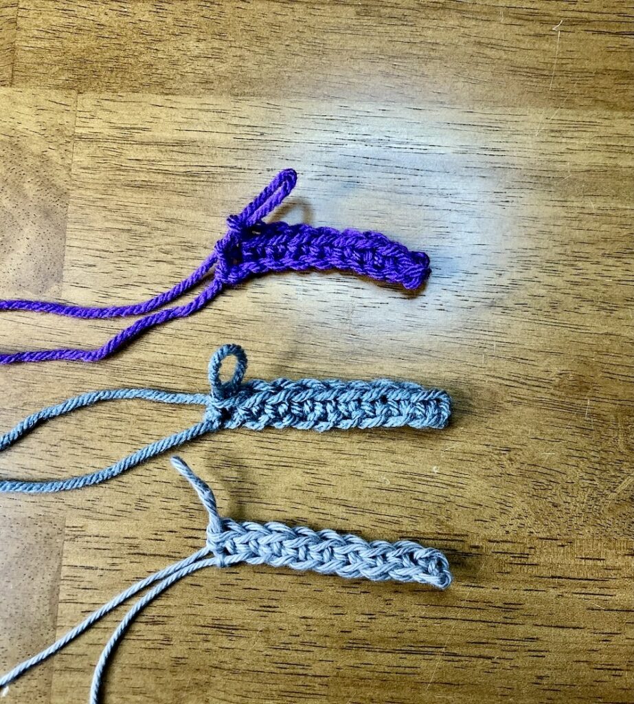 three crochet pieces in dark purple, dark gray and light gray showing the three techniques to crochet into the foundation chain on a wooden background.