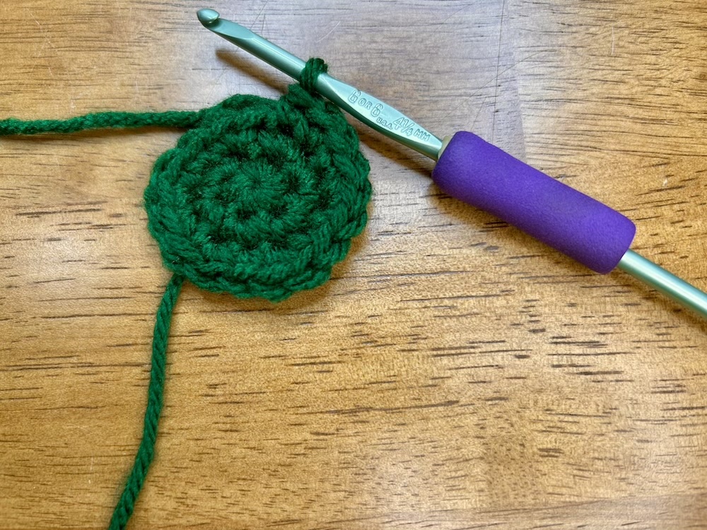 dark green crocheted circle with 3 rounds of stitches.